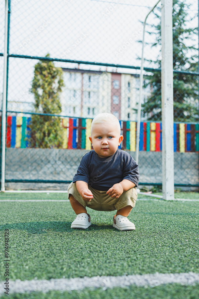 A child is having fun playing in an open field. A little boy in a t-shirt and shorts is playing on the street. Stylish children's clothing. A boy in summer crocs on his feet. A child is having fun playing in an open field. A little boy in a t-shirt and shorts is playing on the street. Stylish children's clothing. A boy in summer crocs on his feet.