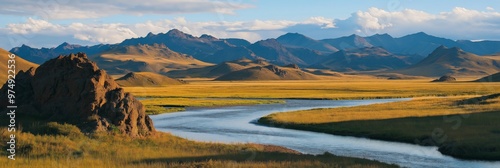 A river runs through a grassy plain with mountains in the background. The scene is peaceful and serene, with the water flowing calmly and the mountains providing a beautiful backdrop