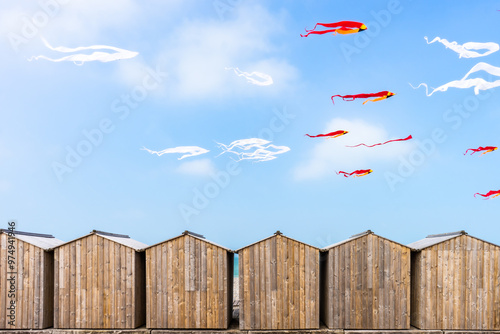 Photos White and red kites flying in blue skies over beach cabins in Dieppe, France