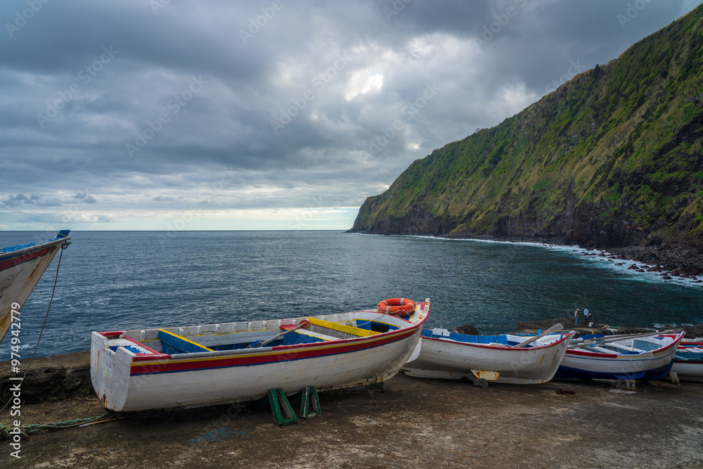 Few boats parked in front of Atlantic Ocean and tall green cliffs near Nordeste village on Sao Miguel island in Azores archipelago Few boats parked in front of Atlantic Ocean and tall green cliffs near Nordeste village on Sao Miguel island in Azores archipelago