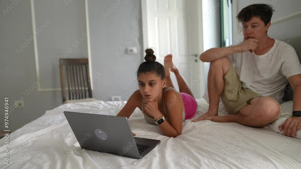 Young friends engaged with a laptop on a bed, enjoying digital interaction in a relaxed setting Young friends engaged with a laptop on a bed, enjoying digital interaction in a relaxed setting