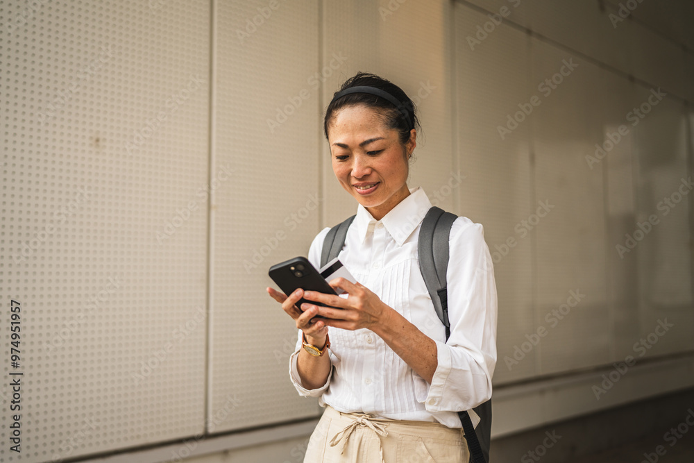 Fototapeta premium japanese woman buy online on cellphone with credit card outdoor