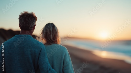 A couple stands close together on a sandy beach, gazing at the setting sun over the ocean horizon, enveloped in a peaceful and romantic atmosphere during twilight. photo