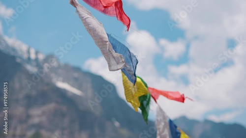 4K Closeup slow motion shot of Buddhist prayer flag waving in the wind in front of snowy Himalayan mountain peaks as seen from Khangsar village in Lahaul and Spiti district, Himachal Pradesh, India. photo