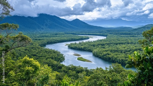 A winding river meanders through lush green rainforest, surrounded by majestic mountains under a cloudy sky.