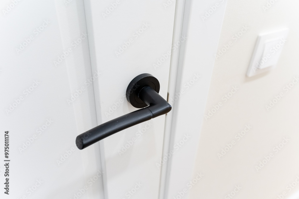 This is a detailed closeup image of a sleek black door handle that is elegantly placed on a pristine white door, showcasing the contrast between the two surfaces beautifully This is a detailed closeup image of a sleek black door handle that is elegantly placed on a pristine white door, showcasing the contrast between the two surfaces beautifully