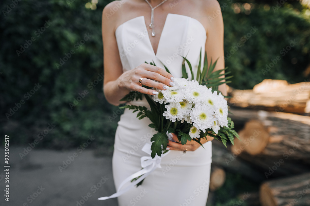 Young beautiful bride holding bouquet with white chrysanthemums outdoors. Wedding photography, portrait. Young beautiful bride holding bouquet with white chrysanthemums outdoors. Wedding photography, portrait.