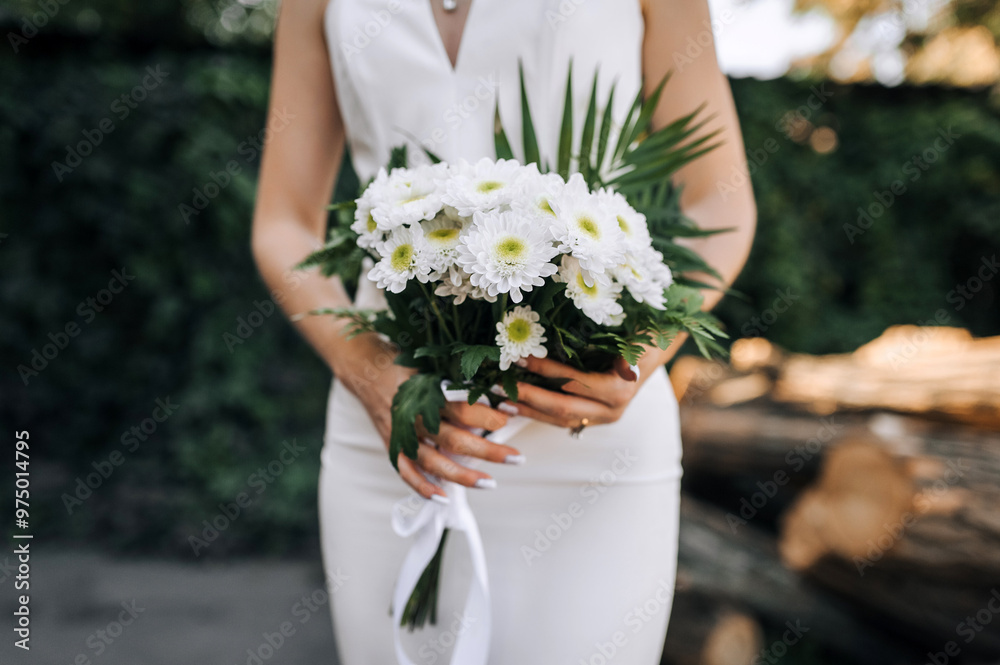 Young beautiful bride holding bouquet with white chrysanthemums outdoors. Wedding photography, portrait. Young beautiful bride holding bouquet with white chrysanthemums outdoors. Wedding photography, portrait.