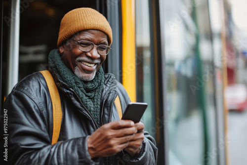 A senior Black male, smiling contentedly as he uses his mobile phone to pay for bus fare, standing near the bus entrance. .jpg