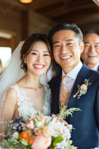 A cheerful Japanese bride and groom posing for a photo with family after their wedding ceremony, both smiling with joy.
