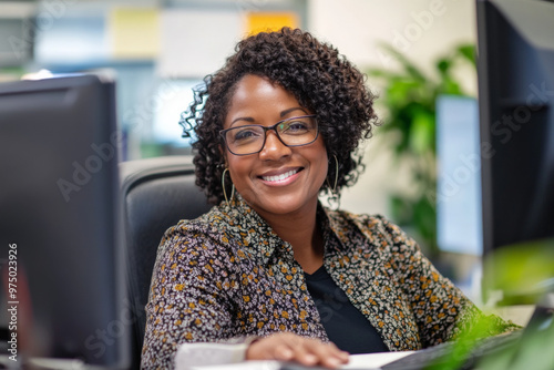 A senior Black female customer support representative with a pleasant smile, looking at the camera while seated at her desk in a calm office.