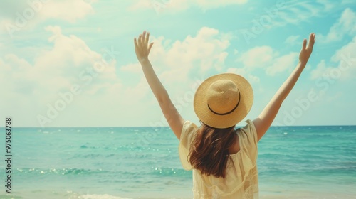 Joyful woman in straw hat raises arms towards the sky, embracing the freedom of a sunny beach day. photo