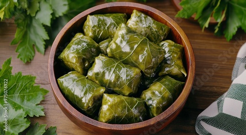 Freshly prepared stuffed grape leaves arranged in a wooden bowl on a rustic t...