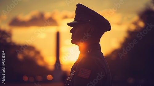 Silhouette of a young soldier at sunset, standing in profile, paying respect at a memorial site, representing military service and sacrifice.