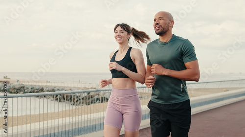 Running woman and man enjoy their summer morning workout. Team sports. Couple goals and motivation. Happy fit people are cheerfully doing sports photo