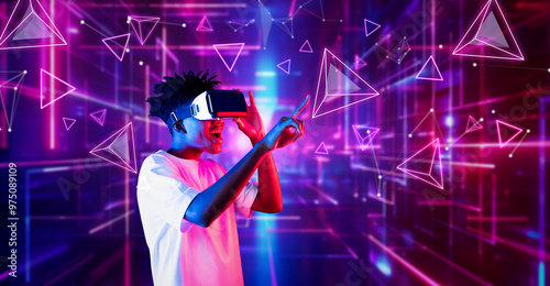 Smart teenager wearing VR glasses and excited about geometric shape. African gamer wearing casual cloth and surrounded with glowing light color while using augmented reality technology. Ingenuity. photo