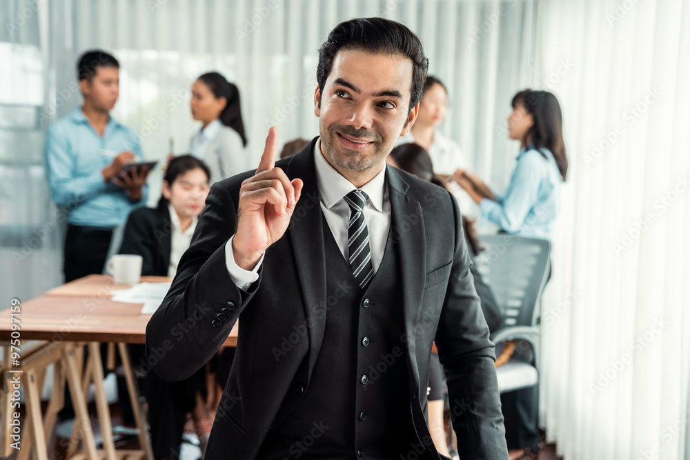 Portrait of happy businessman looking at camera, making finger pointing gesture for advertising product with motion blur background of business people movement in dynamic business meeting. Habiliment Portrait of happy businessman looking at camera, making finger pointing gesture for advertising product with motion blur background of business people movement in dynamic business meeting. Habiliment
