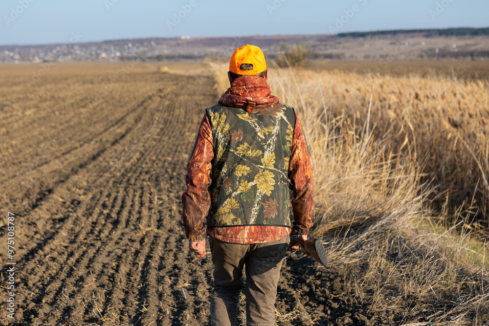 Mature man hunter with gun while walking on field. Mature man hunter with gun while walking on field.
