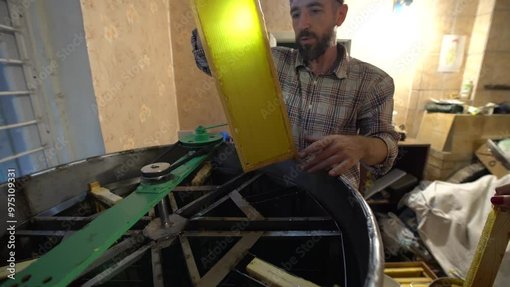 Beekeeper takes out the honeycomb frames with honey from the honey extractor and inspects Beekeeper takes out the honeycomb frames with honey from the honey extractor and inspects