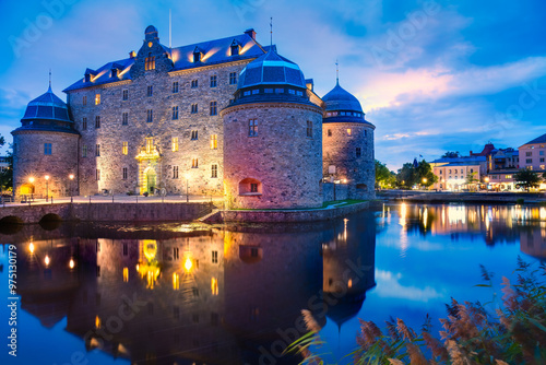 Illuminated medieval Orebro Castle is a fortification at Svartan river by night . Tourist atraction and history entusiast destination. Sweden. Copy space