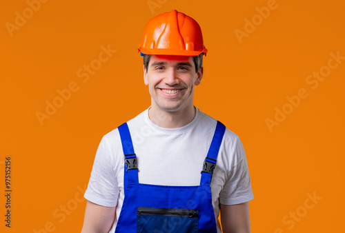 Friendly handyman smiling portrait on orange studio. Positive builder man,helmet