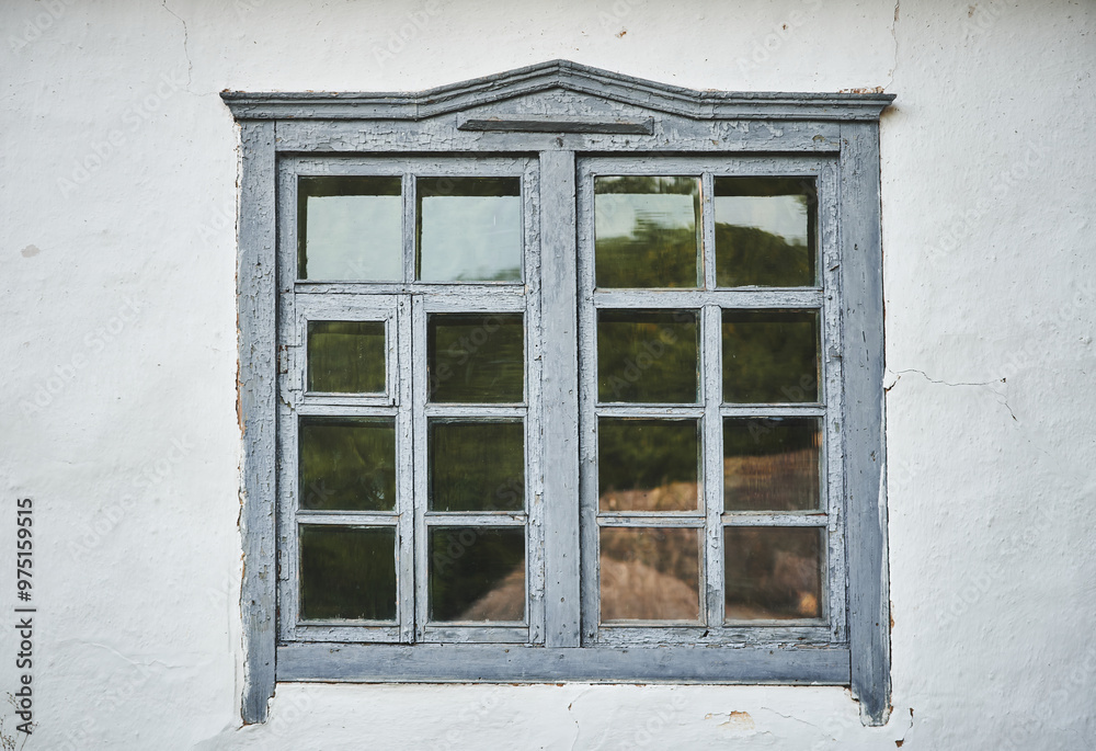 Close-up of an old grey wooden window on a white wall. Part of an old house with painted and weathered window Close-up of an old grey wooden window on a white wall. Part of an old house with painted and weathered window