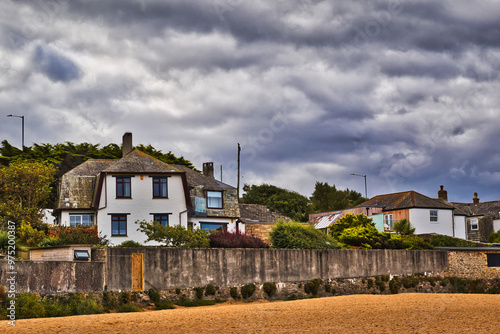 Coastal Houses Under Dramatic Clouds at Mawgan Porth Beach, Newquay, Cornwall photo