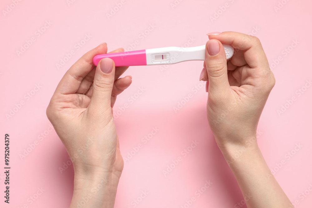 Woman holding pregnancy test on pink background, closeup Woman holding pregnancy test on pink background, closeup