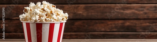 delicious popcorn in a striped bucket on a wooden background