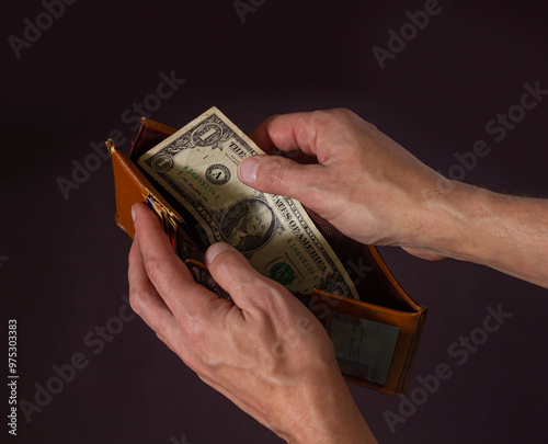 Male hands hold open an old wallet with one dollar photo