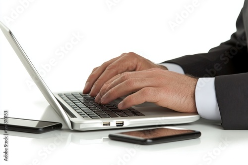 Close up of man's hands typing on laptop with a cell phone on the table beside it.