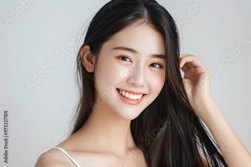 A woman with long hair is smiling and has her hair blowing in the wind