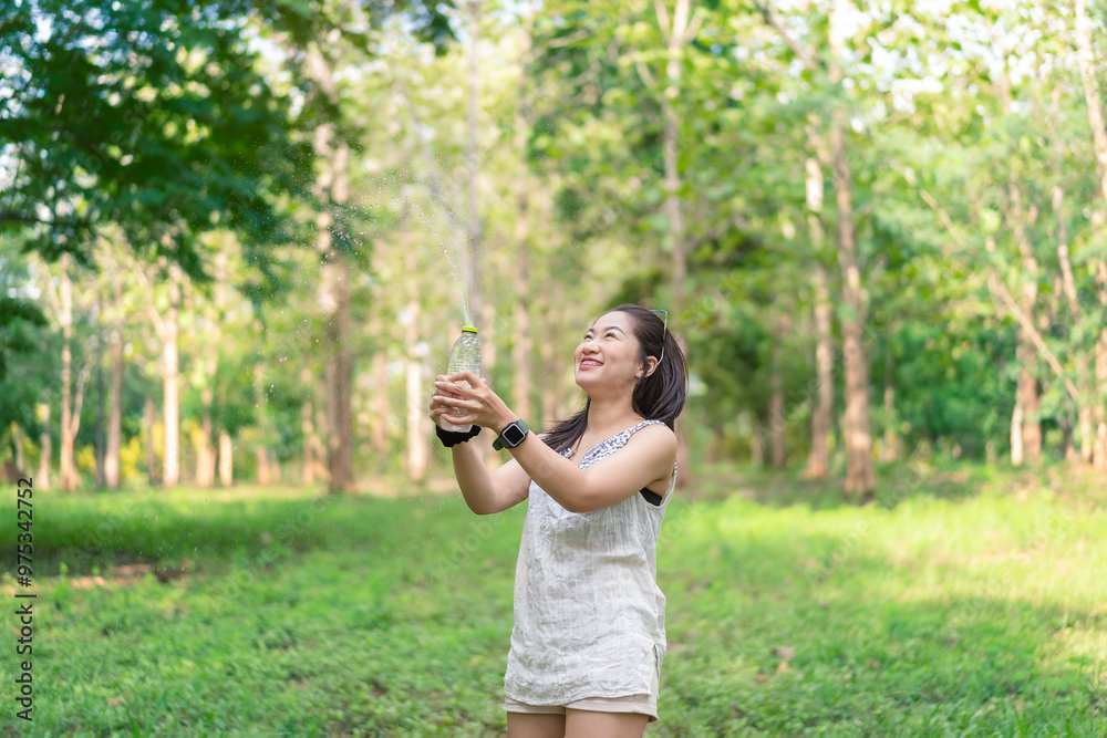 Happy young woman holding a water bottle in her hand Her cheerful demeanor and relaxed demeanor reflect the happiness she finds in her peaceful surroundings. Lifestyle of happiness. Happy young woman holding a water bottle in her hand Her cheerful demeanor and relaxed demeanor reflect the happiness she finds in her peaceful surroundings. Lifestyle of happiness.