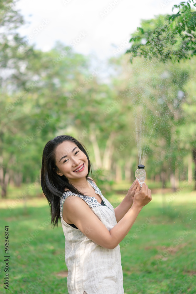 Happy young woman holding a water bottle in her hand Her cheerful demeanor and relaxed demeanor reflect the happiness she finds in her peaceful surroundings. Lifestyle of happiness. Happy young woman holding a water bottle in her hand Her cheerful demeanor and relaxed demeanor reflect the happiness she finds in her peaceful surroundings. Lifestyle of happiness.