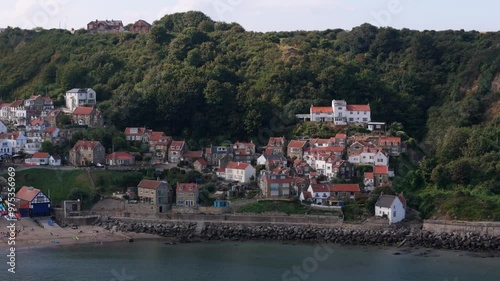 Aerial footage of Runswick Bay, a scenic village in North Yorkshire with cliffs, ocean and a sandy beach with cottages and countryside photo