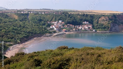 Aerial footage of Runswick Bay, a scenic village in North Yorkshire with cliffs, ocean and a sandy beach with cottages and countryside photo