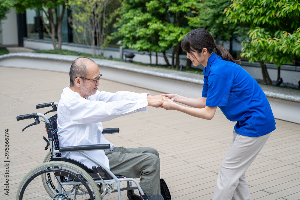 車いすから立ち上がる介助をする介護施設スタッフ 車いすから立ち上がる介助をする介護施設スタッフ