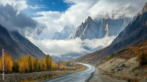 Breathtaking view of Passu Cones draped in clouds, a peaceful paved road winding along the Karakoram Highway through Gojal, Hunza Valley in Gilgit Baltistan.