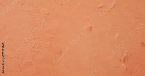 a close-up view of a textured orange surface, possibly a fabric or a material, with small, indistinct dots or specks scattered across it.