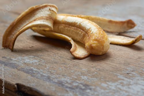 half peeled over ripe banana with creamy flesh exposed on table top surface, almost rotten or spoiled, unappealing fruit in selective focus with copy space photo