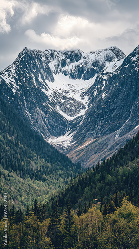 Majestic Swedish mountains with snow capped peaks rise dramatically above lush green valley, creating breathtaking landscape that evokes sense of tranquility and awe