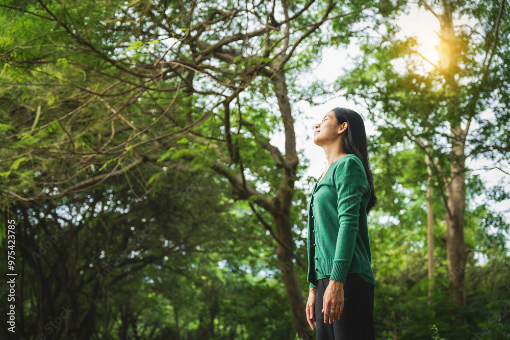 confident asian woman embraces self-love, standing peacefully in serene park at sunset. joyful smile, she enjoys fresh air, breathing deeply, radiates calm and positivity in tranquil surroundings.