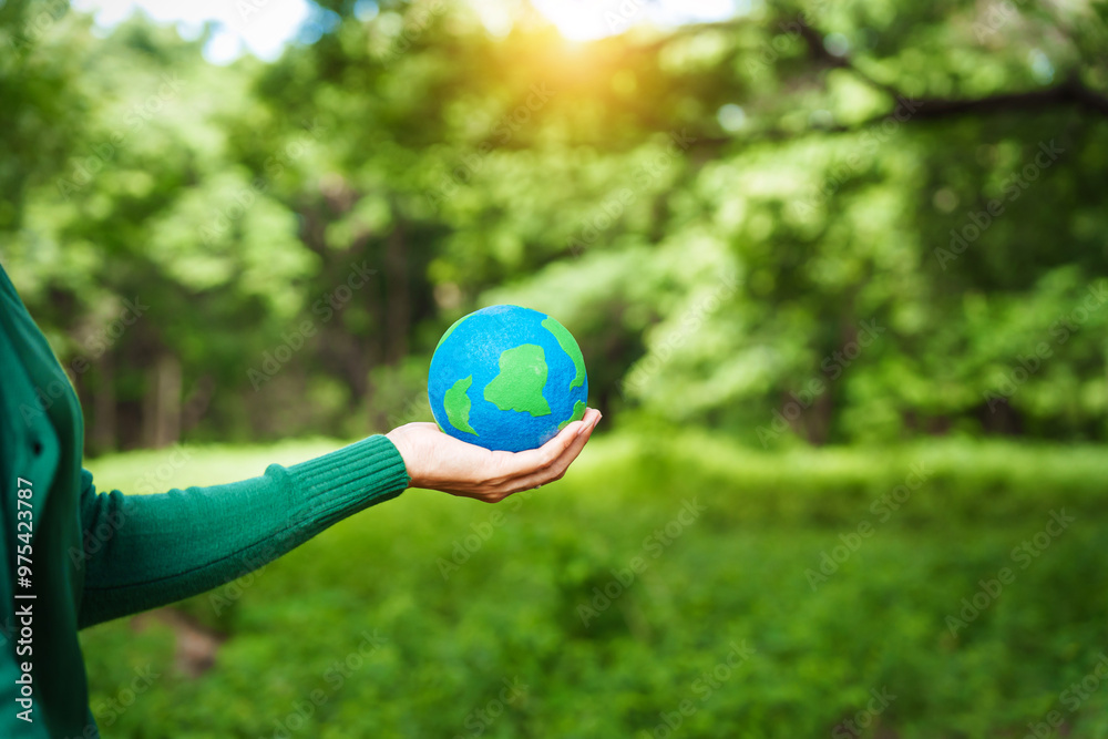 Forest conservationist holds small globe in hands, symbolizing global responsibility for protecting planet. Standing outdoors in green park, sustainability, commitment to achieving net-zero impact. Forest conservationist holds small globe in hands, symbolizing global responsibility for protecting planet. Standing outdoors in green park, sustainability, commitment to achieving net-zero impact.