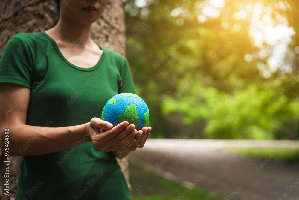 Forest conservationist holds small globe in hands, symbolizing global responsibility for protecting planet. Standing outdoors in green park, sustainability, commitment to achieving net-zero impact. Forest conservationist holds small globe in hands, symbolizing global responsibility for protecting planet. Standing outdoors in green park, sustainability, commitment to achieving net-zero impact.