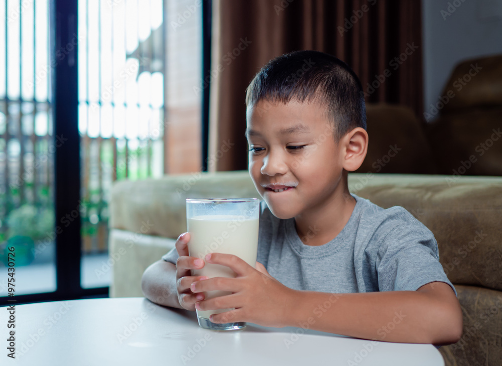 Portrait of a little young handsome kid boy in pink t-shirt, Concept of happy good nutrition, Holding a glass of milk on grey background, Smiling of Asian boy with a glass of milk. Portrait of a little young handsome kid boy in pink t-shirt, Concept of happy good nutrition, Holding a glass of milk on grey background, Smiling of Asian boy with a glass of milk.