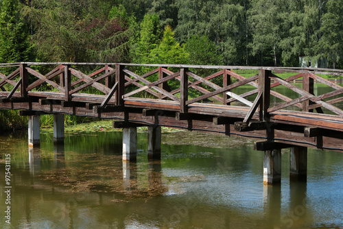 Wooden bridge over river. Nature in botanical park, countryside and structures in summer. 