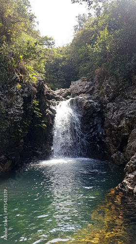 A serene waterfall pouring down into large natural swimming pool, surrounded by lush greenery and rocky formations, creates tranquil atmosphere perfect for relaxation