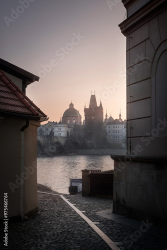 Charles Bridge with Old town Tower over Vltava river in Prague in the early morning during sunrise. Paddle stone road in the foreground. 