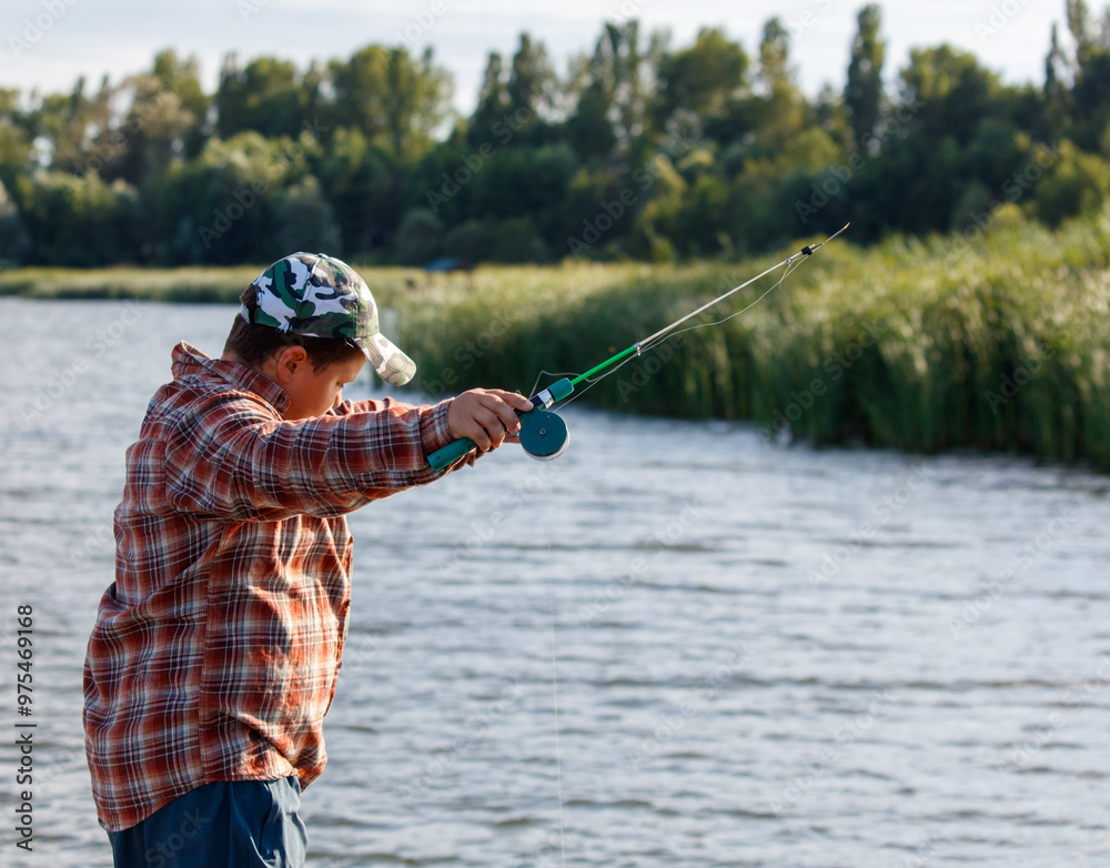 A boy is fishing with a small fishing rod on a pond A boy is fishing with a small fishing rod on a pond