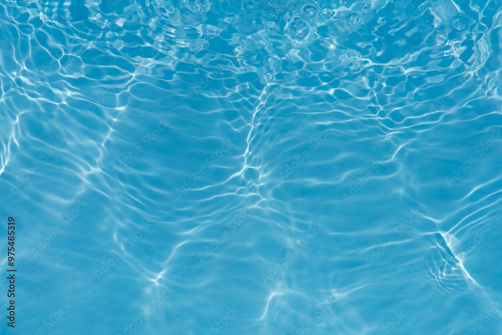 Obraz premium Blue water with ripples on the surface. Defocus blurred transparent blue colored clear calm water surface texture with splashes and bubbles. Water waves with shining pattern texture background.